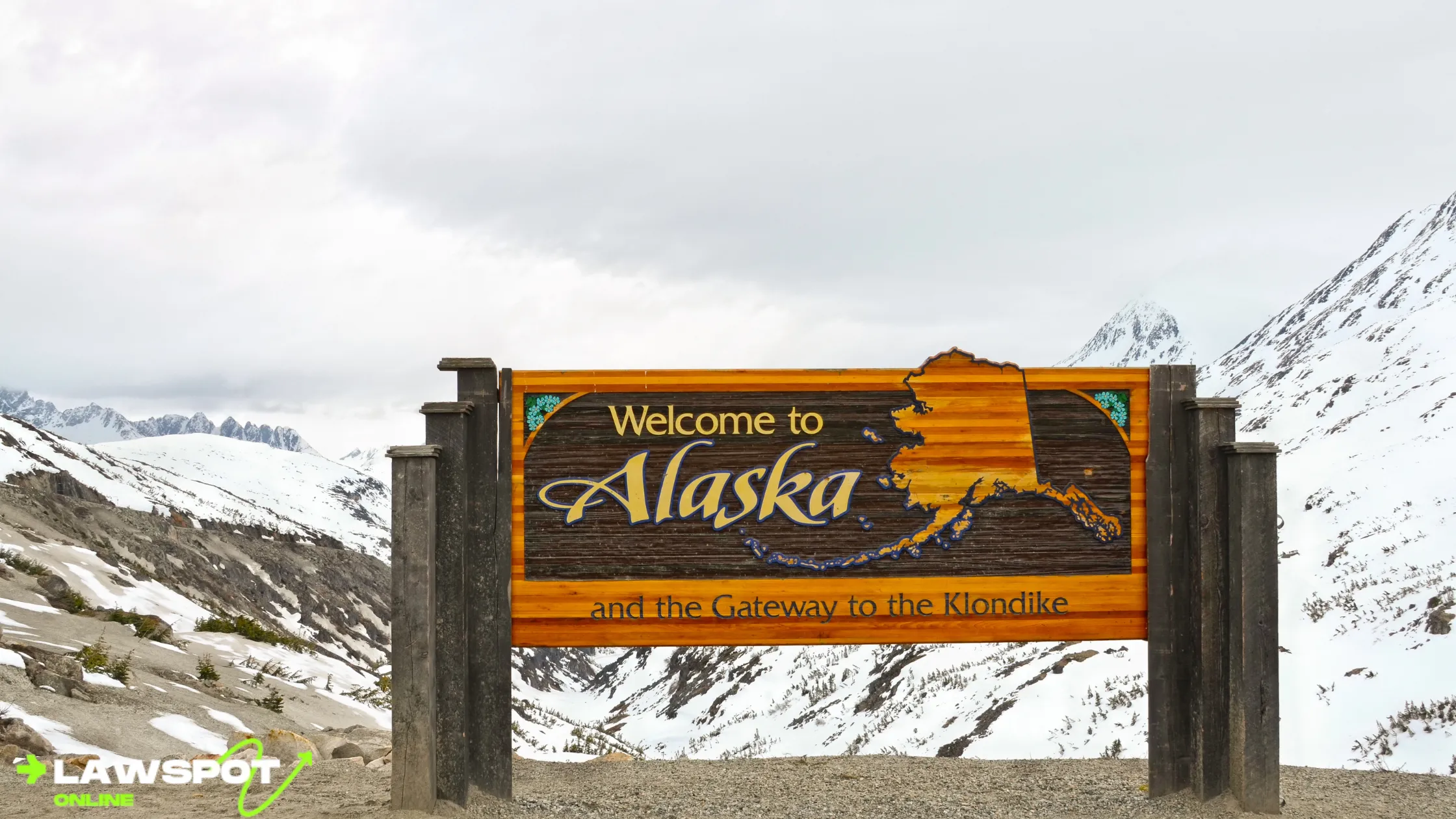 Welcome to Alaska sign with snow-covered mountains in the background, highlighting the breathtaking scenery encountered along the drive. Can you drive to Alaska? Yes, and this view greets travelers as they enter the state.